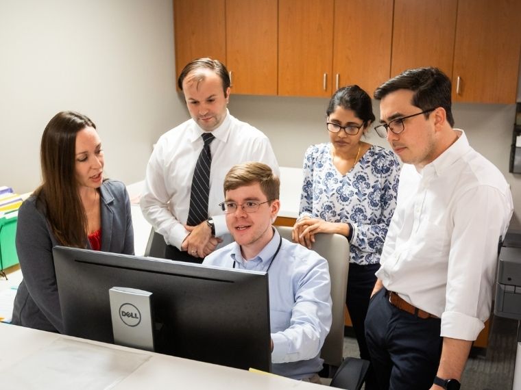 A group of fellows and faculty member review data on a computer monitor.